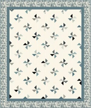 A quilt featuring a repeated pinwheel pattern in muted shades of blue, gray, black, and white, set on a cream background with a blue floral border.
