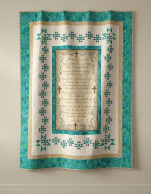A decorative quilt with teal and cream star patterns, features a central panel with ornate borders and gold script text displaying the lyrics to Amazing Grace, hung on a beige wall.