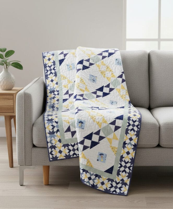 A colorful patchwork quilt in blue, yellow, white, and green geometric patterns is draped over a light gray sofa in a bright, modern living room with a wooden side table and potted plant nearby.