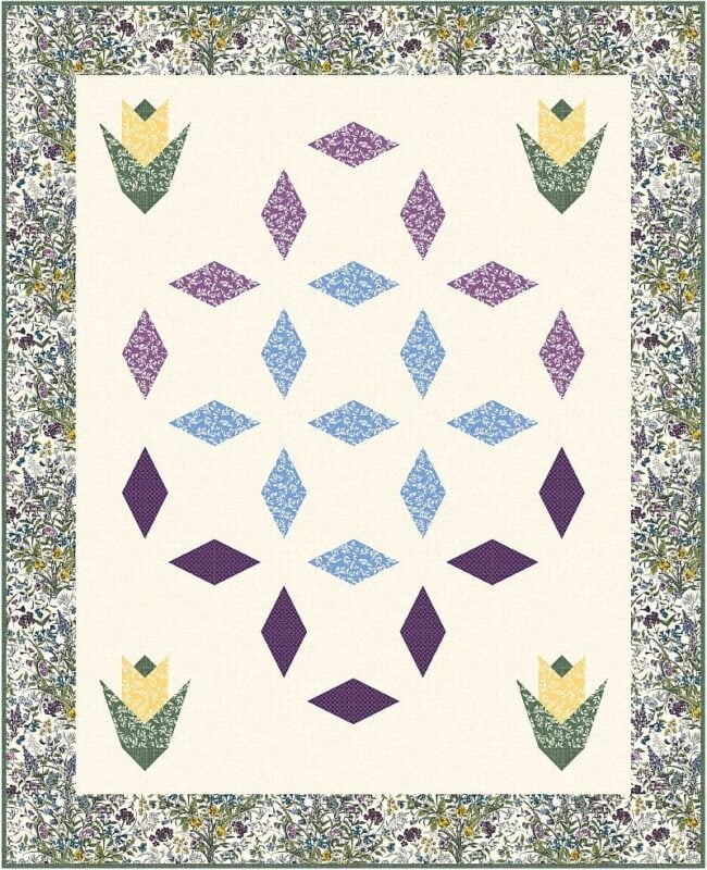Gem-Dandy quilt with a floral border, featuring three yellow and green tulip shapes in the corners and a central geometric pattern of purple and blue diamond shapes on a cream background.