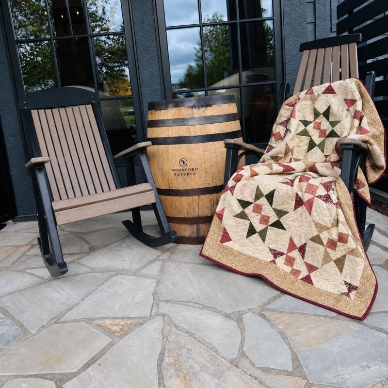 Cider and Cloves quilt draped over a wooden rocking chair on a stone patio